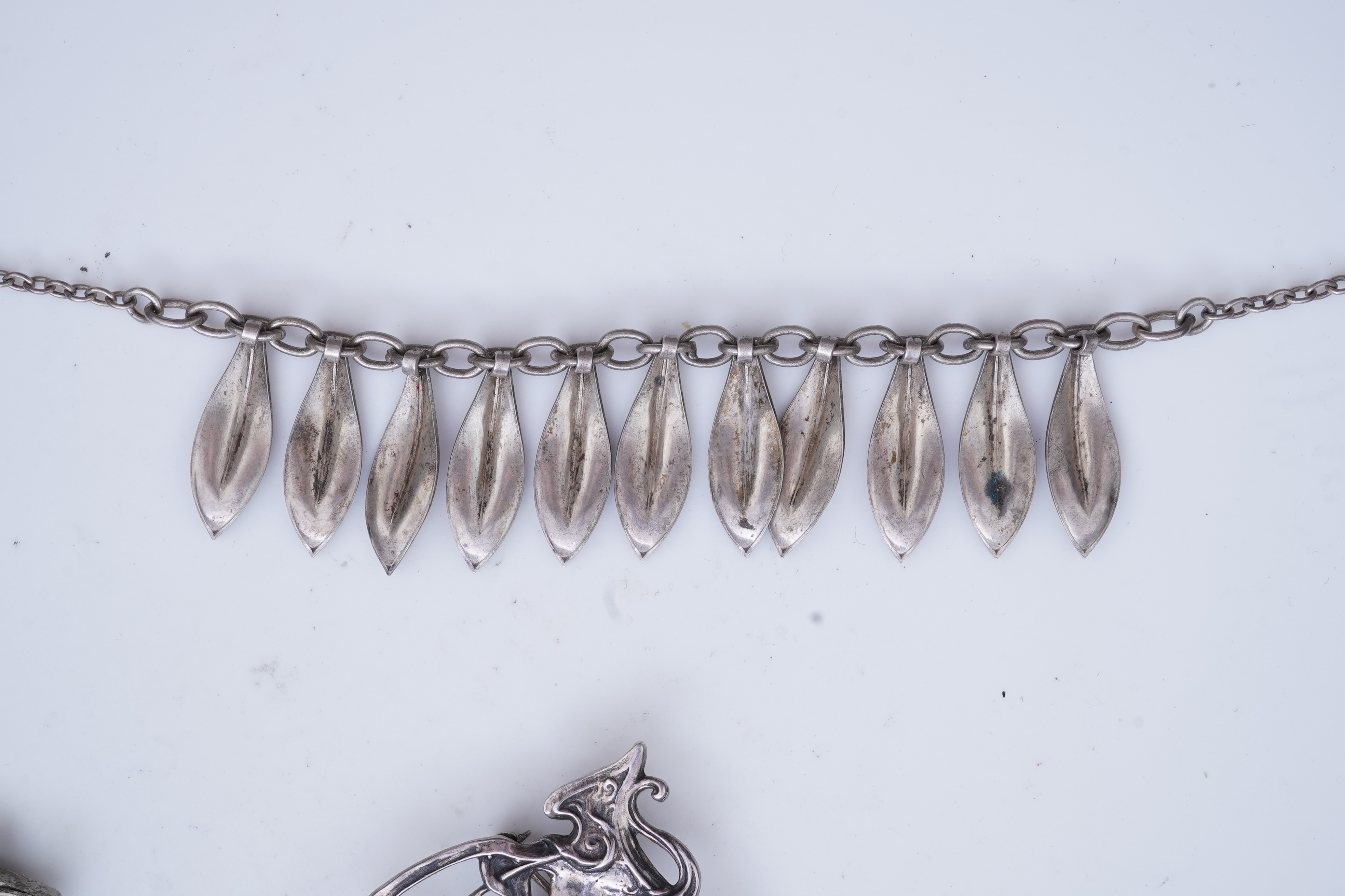 A collection of three silver chains and an Art Nouveau brooch, early 20th century